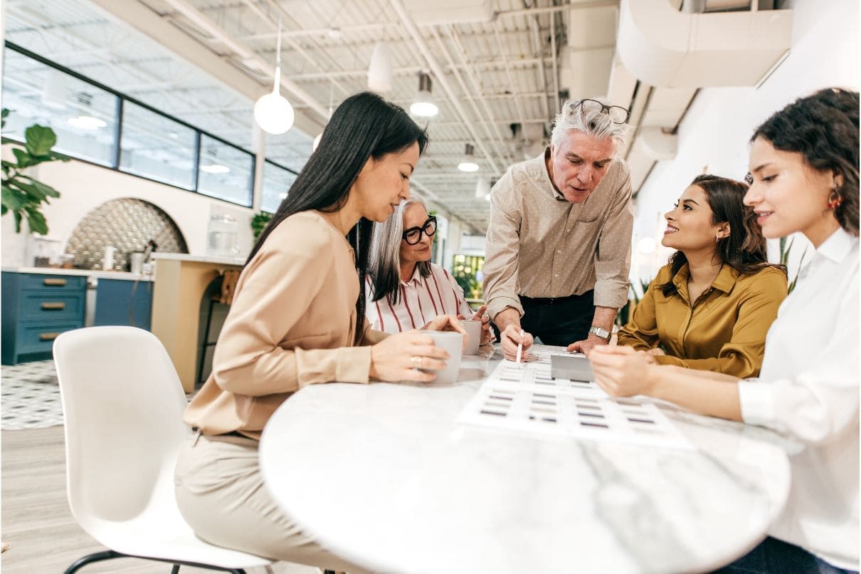 A diverse group of individuals, including a man and a woman, gathered around a table engaged in conversation and collaboration.